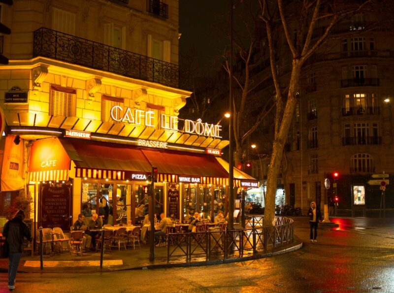 冬のパリ、温かい光が灯るブラッスリーの風景。フランス語の日常会話が聞こえてきそうな、落ち着いた冬の街角。