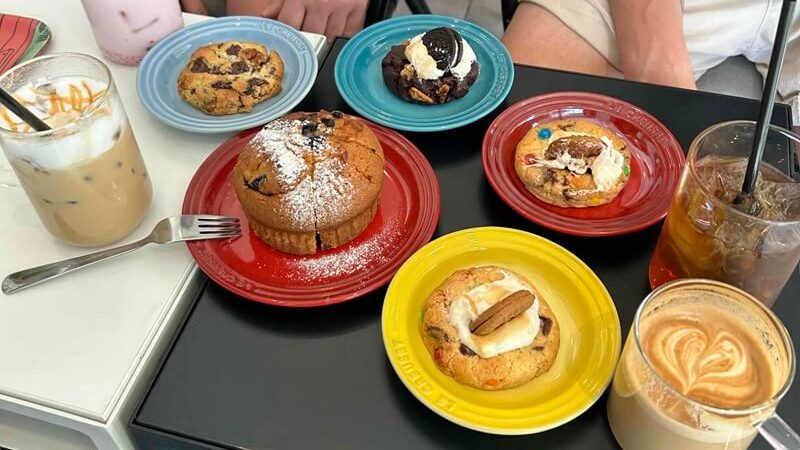 韓国の可愛いカフェで、机に並べられた美味しそうなパティスリー（ケーキや焼き菓子）。フランス人友人たちと、心地よいバカンスのようなカフェタイムをイメージした写真。