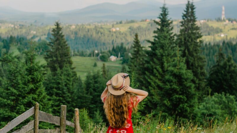緑の自然の中で赤いワンピースを着た女性が立っている夏の風景